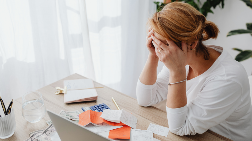 A stressed woman looking at receipts thinking, "why am I so bad with money?"