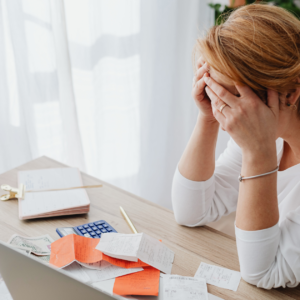 A stressed woman looking at receipts thinking, "why am I so bad with money?"